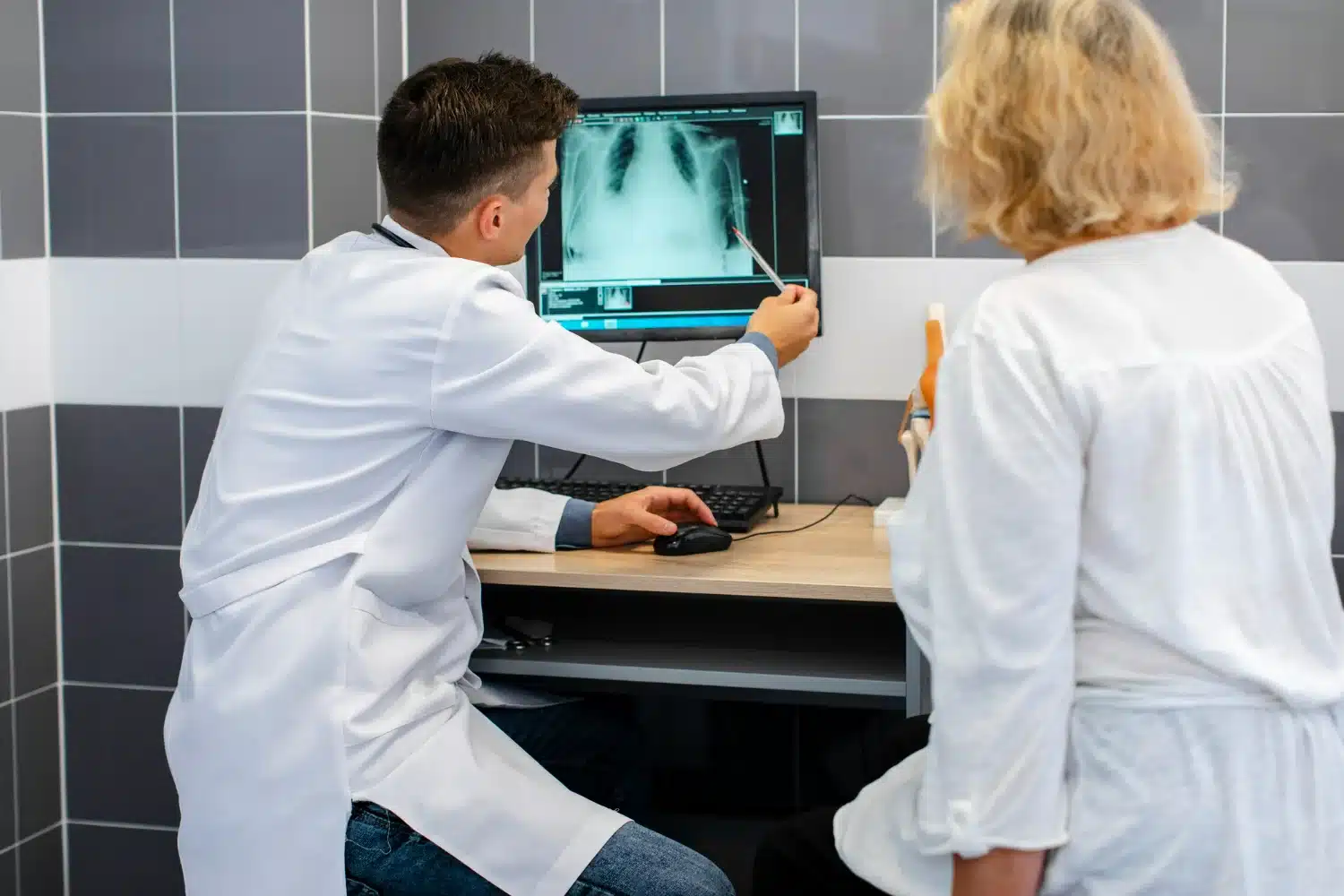 Técnico em radiologia explicando exame de imagem. Técnico em radiologia explicando exame de raios-X para paciente em consultório médico.