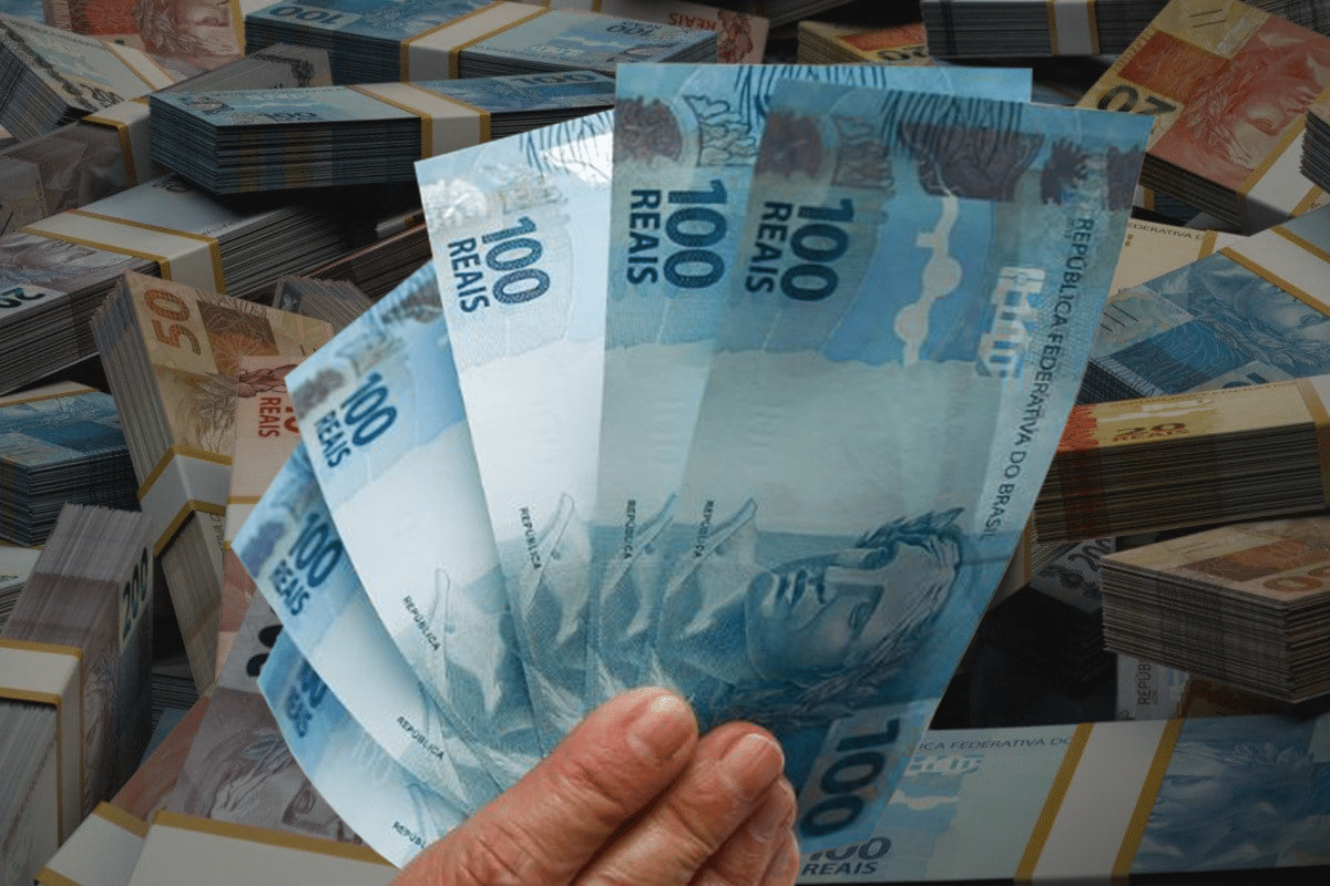 Mão segurando cédulas de 100 reais.