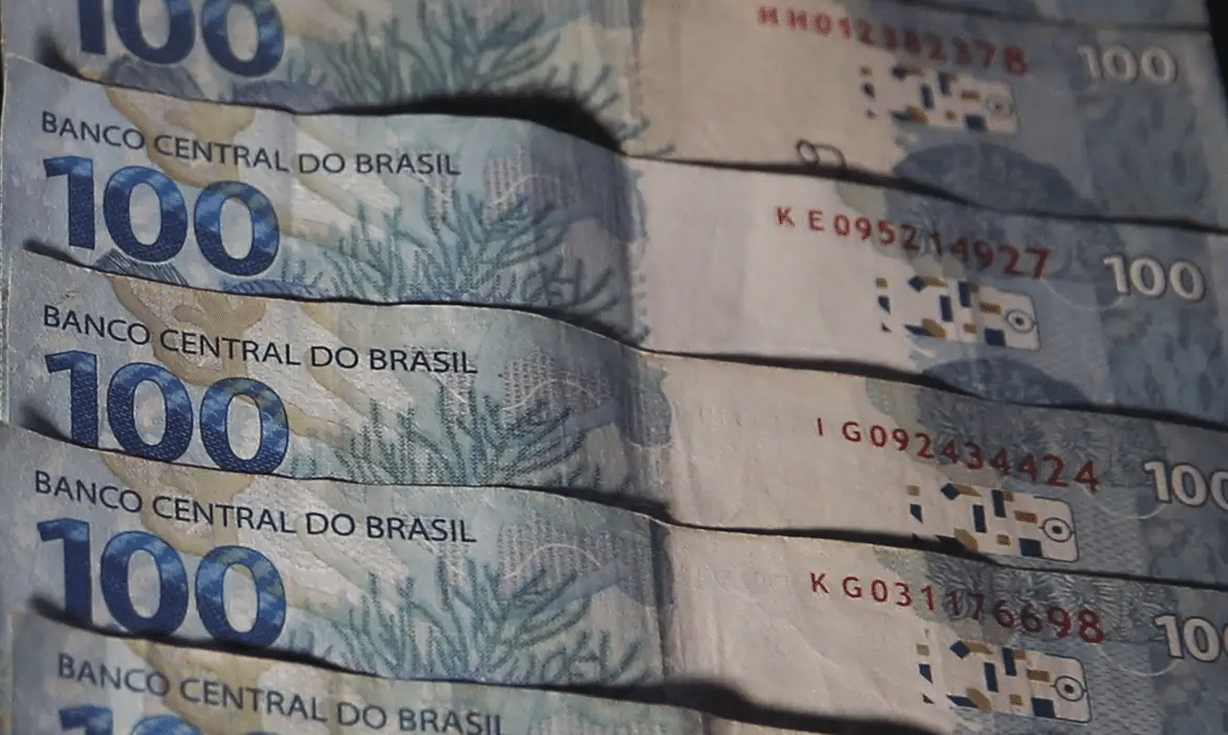 Cédulas de 100 reais empilhadas, Banco Central do Brasil em destaque.