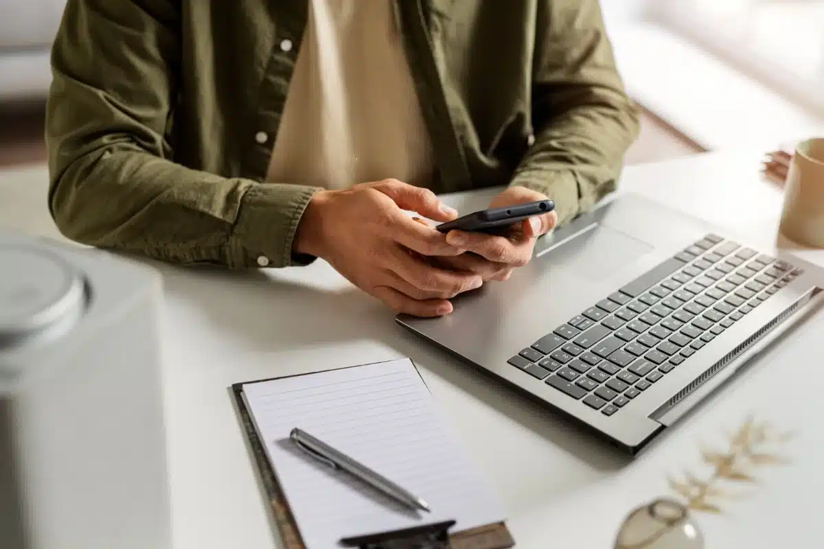 Estudo de informática e suas abordagens em provas. Pessoa usando o celular e o computador durante estudo de informática.