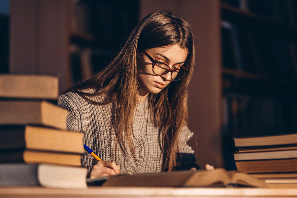 Estudante concentrada estudando para concursos legislativos com livros ao redor