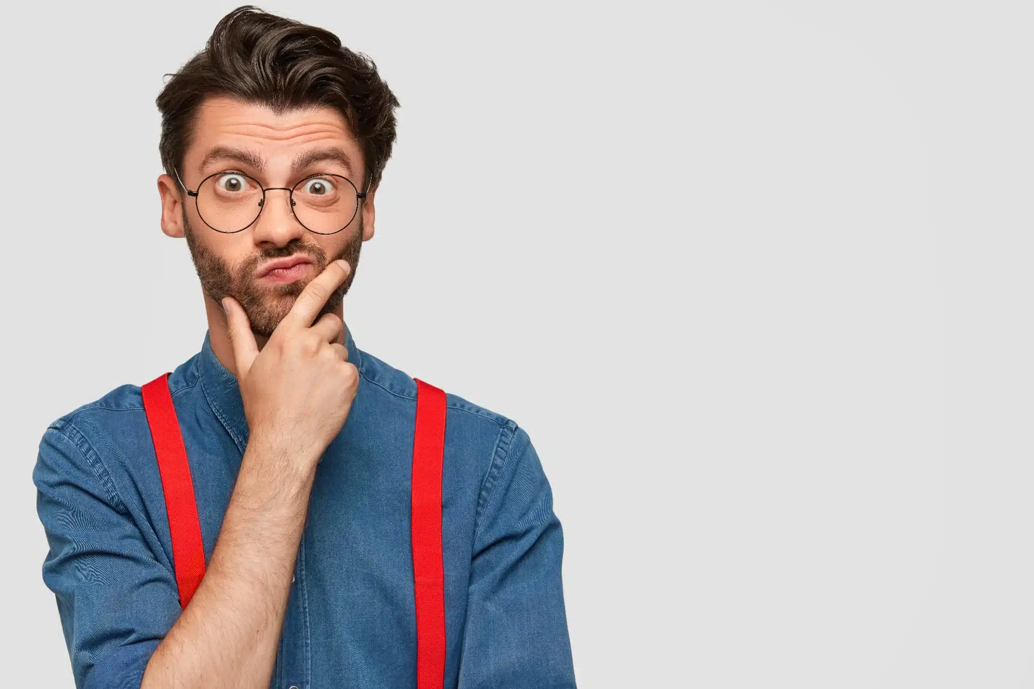 Homem com suspensórios vermelhos, pensando sobre curiosidades da língua portuguesa.