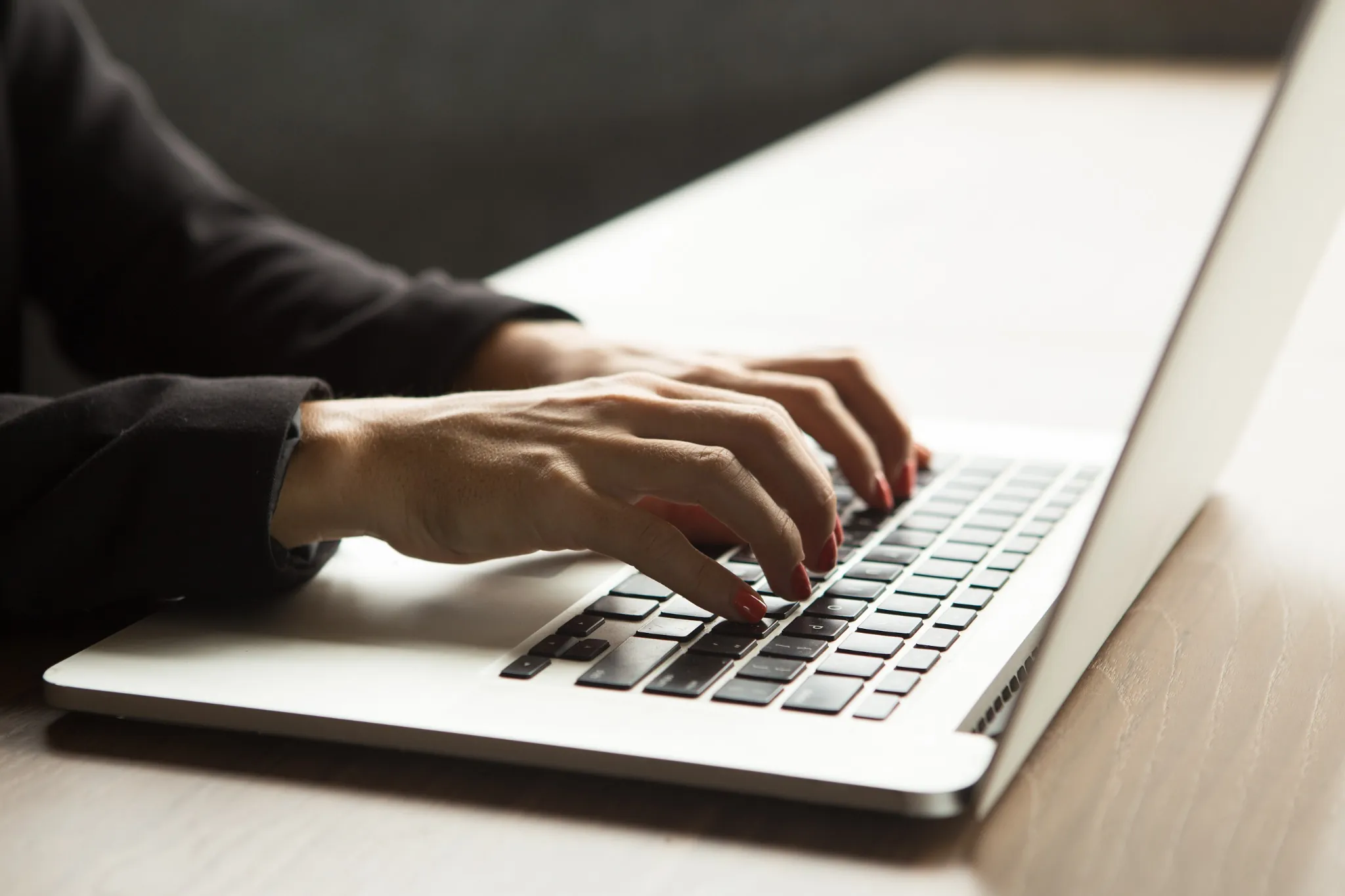 Concurso Público Mãos femininas digitando em notebook sobre mesa de madeira
