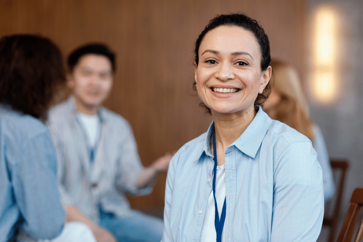 Mulher sorridente sentada em círculo, participando de reunião em grupo