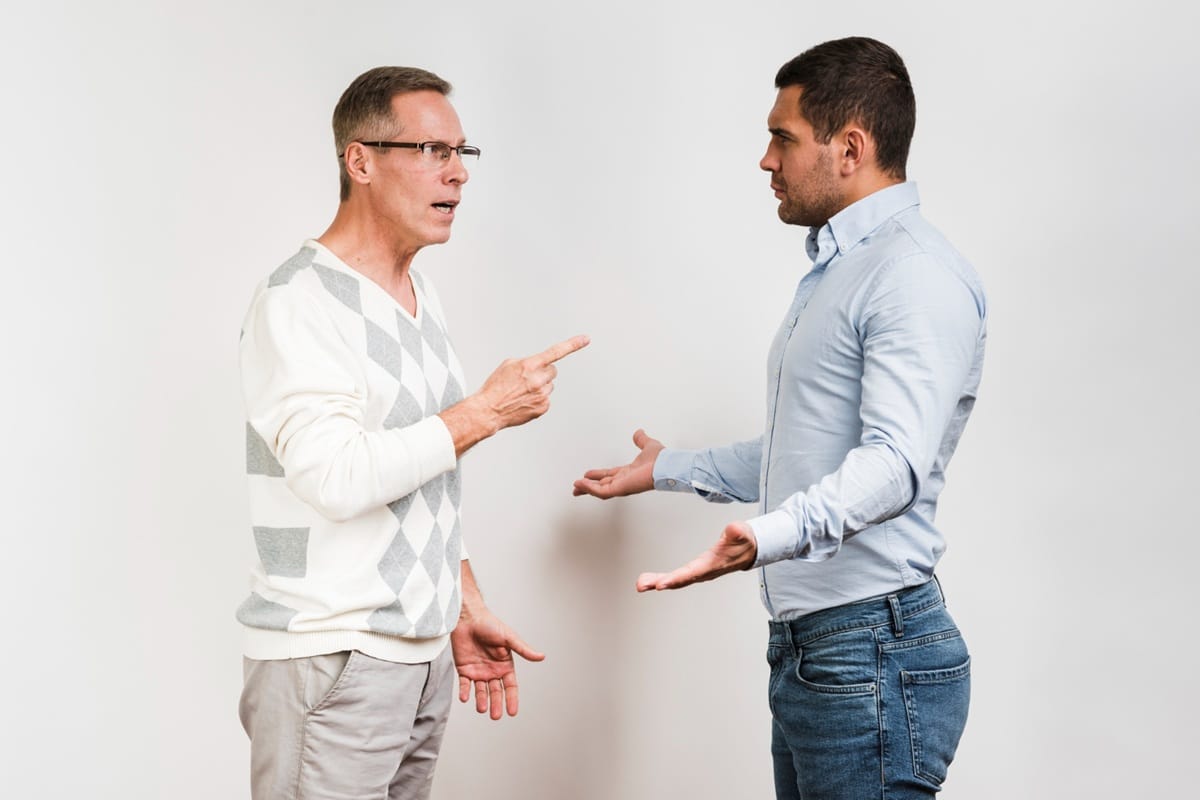 Dois homens em discussão acalorada exemplificando comunicação arrogante através de linguagem corporal defensiva