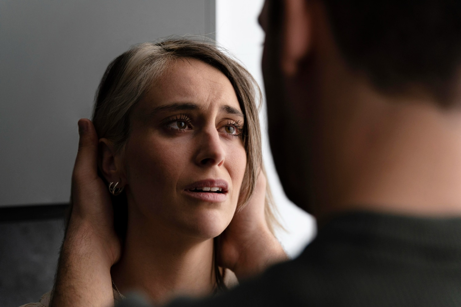 Mulher com expressão triste e emocionada enquanto é confortada por outra pessoa.