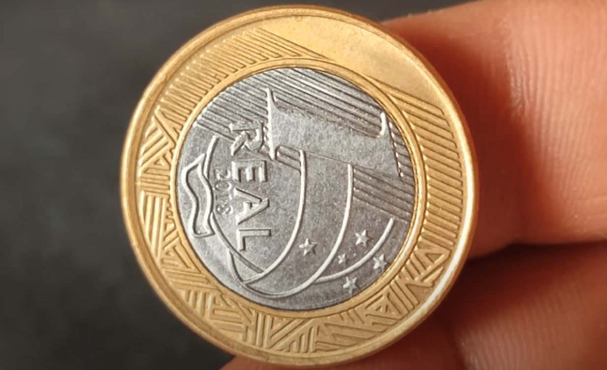 Moeda de 1 Real com Reverso Horizontal Moeda de 1 real de 2018 em close-up, mostrando o erro de cunhagem onde o reverso (o rosto da República) está de lado, simbolizando uma anomalia rara.