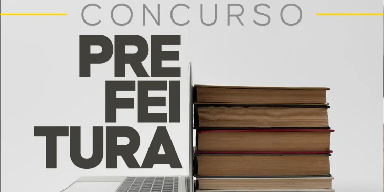 Notebook aberto ao lado de livros empilhados simbolizando estudo para concurso da prefeitura