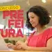 Mulher usando laptop em biblioteca, focada em inscrição para concurso da prefeitura.