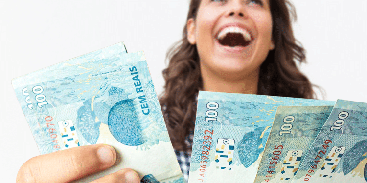 Mulher sorridente segurando várias notas de 100 reais olhando para cima com expressão de felicidade