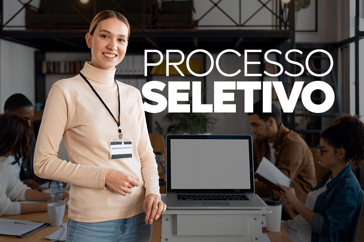 Requisitos divulgados para seleção com salários de R$ 5.100 Mulher sorridente de blusa bege com crachá ao lado de notebook em escritório moderno com texto Processo Seletivo