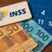 Notas de dinheiro, logo do INSS e calendário.