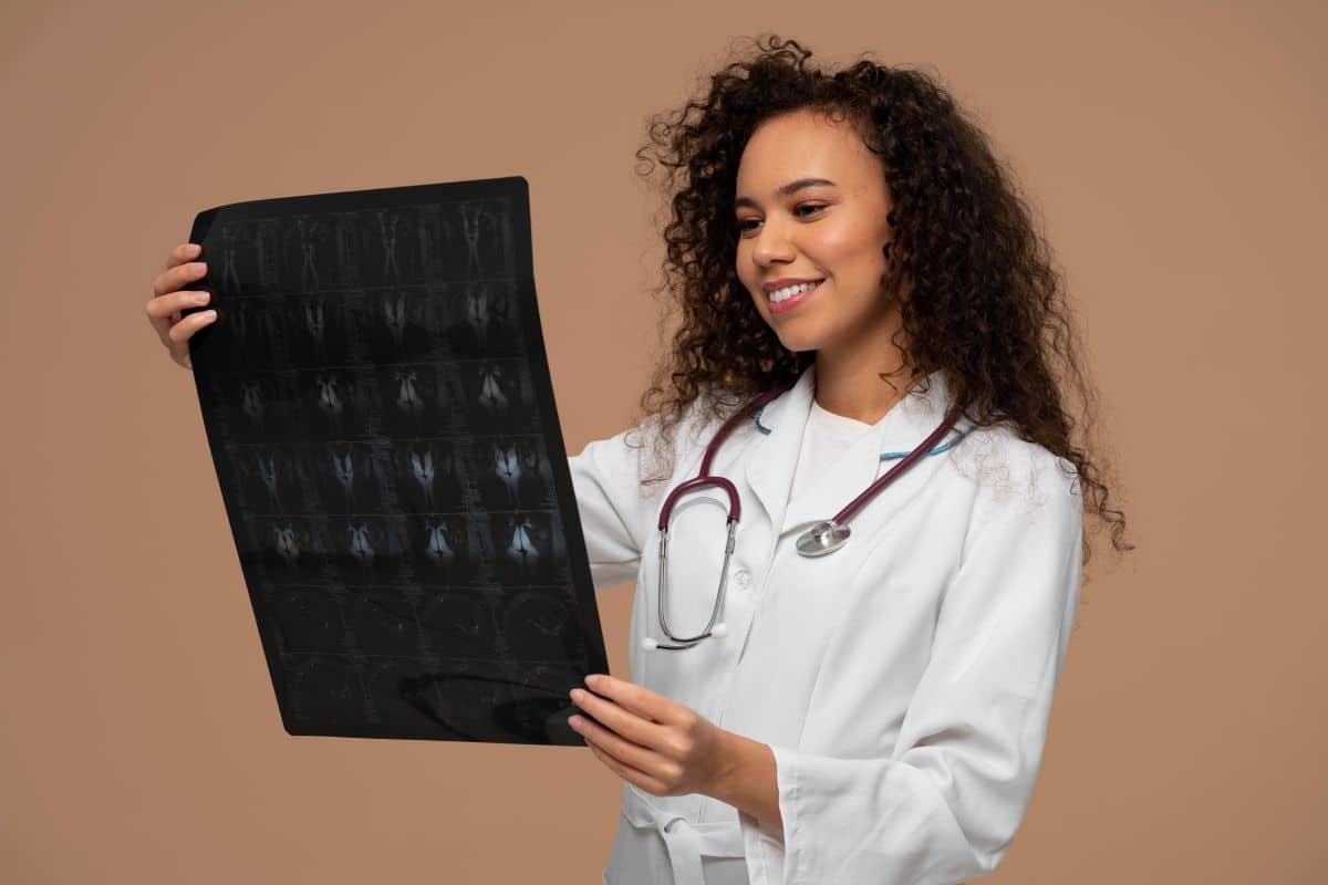 Carreira de Técnico em Radiologia Médica radiologista sorrindo enquanto analisa uma chapa de raio-x, representando o sucesso na carreira de diagnóstico por imagem.