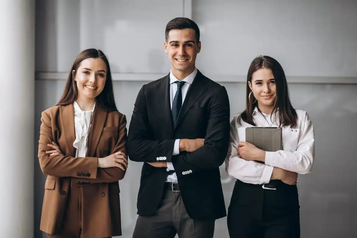 Profissionais de alto nível em escritório com foco em áreas de alta remuneração. Três profissionais sorrindo em um ambiente de escritório, destacando áreas com alta remuneração como diretoria, tecnologia e jurídico.