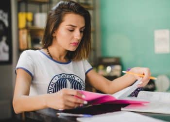 Candidata organizando materiais de estudo com marca-textos para preparação da redação