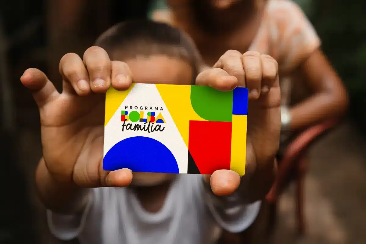 Bolsa Família: Pagamentos de Outubro e Planejamento Familiar Mãos de uma criança segurando o cartão do Programa Bolsa Família em foco, simbolizando o impacto direto dos pagamentos nas famílias beneficiárias a partir de 20 de outubro.