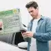 Homem segurando sua Carteira Nacional de Habilitação (CNH) física enquanto utiliza o smartphone para acessar informações sobre o documento.