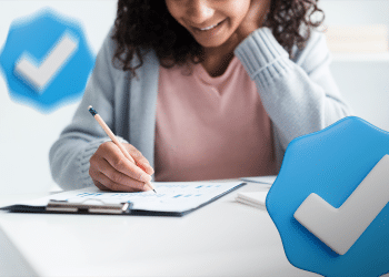 Pessoa sorrindo analisando gráficos em papel com símbolos de verificação azul ao redor.