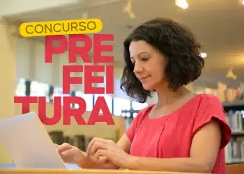 Mulher em biblioteca usando notebook para estudar o edital do Concurso Público da Prefeitura. Representa a busca por vagas de nível médio, técnico e superior.