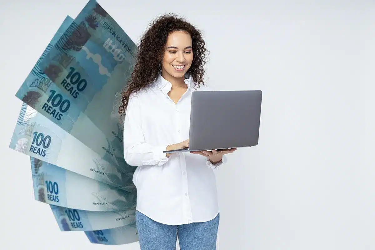 Previsão do reajuste do salário mínimo em 2026: aumento de 7,44% Mulher sorridente com laptop, destacando o reajuste do salário mínimo para 2026, com cédulas de 100 reais ao fundo