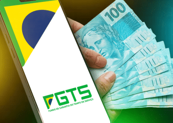 Smartphone exibindo logo FGTS ao lado de leque de notas de cem reais representando valores de antecipação do saque-aniversário