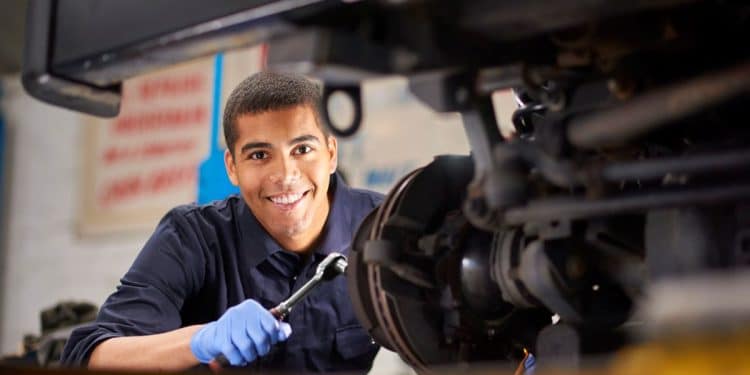 Técnico em mecânica automotiva realizando manutenção com ferramenta.