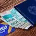 Carteira de trabalho brasileira ao lado de cédulas de dinheiro e cartão PIS/PASEP sobre mesa de madeira.