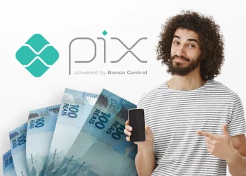 Jovem sorridente apontando para celular com notas de cem reais e logo do Pix ao fundo, simbolizando recebimento de valores