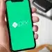 Imagem de um smartphone exibindo o logo do Pix, sistema de pagamentos do Banco Central, com fundo verde, representando o novo botão de contestação para segurança nas transações.