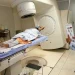 Mulher recebendo radioterapia em hospital com profissional de saúde operando aparelho
