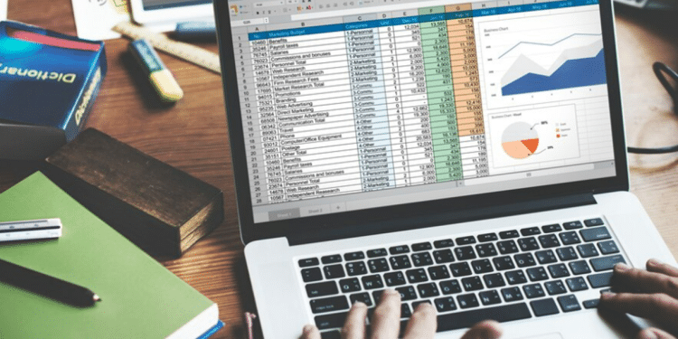 Pessoa trabalhando em um notebook que exibe uma complexa planilha de dados e gráficos no Microsoft Excel, simbolizando a análise corporativa e o uso da ferramenta no dia a dia profissional.