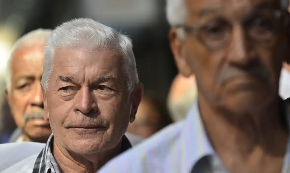 Grupo de idosos com expressão séria Idosos de cabelos brancos com expressões sérias e pensativas em ambiente interno desfocado