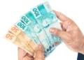 Mãos segurando cédulas de real representam o Saque Calamidade do FGTS, que permite a retirada de até R$ 6.220.