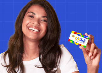 Jovem beneficiária sorridente mostrando cartão Pé-de-Meia em fundo azul