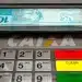 Dinheiro (notas de R$ 100) sendo sacado em caixa eletrônico da CAIXA. Ilustra o Saque do FGTS Calamidade para moradores de cidades afetadas por desastres naturais.