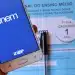 Tela de smartphone exibindo o aplicativo Enem e caderno azul do 1º dia do exame com caneta ao fundo