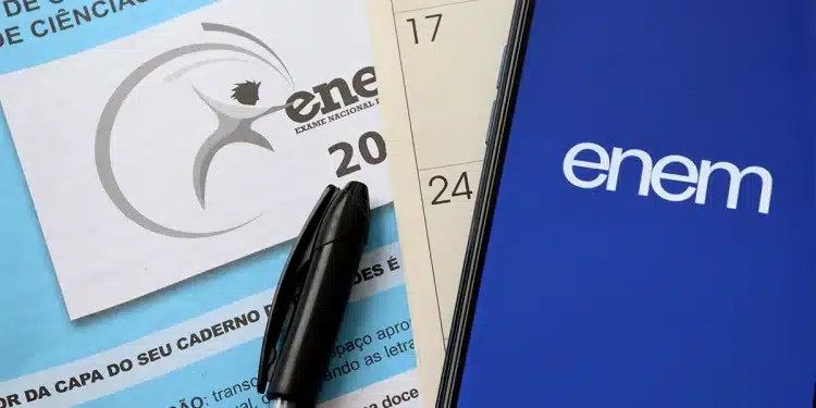 Caderno do ENEM e celular com logo do exame em fundo azul.