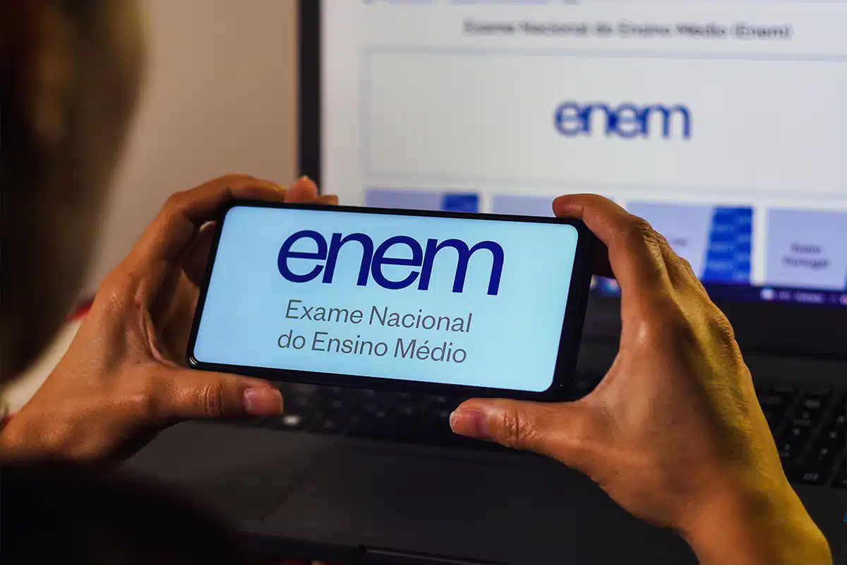 Atenção ao Cronograma: Datas Finais de Solicitação e Reaplicação do Enem 2025 no Edital Pessoa olhando atentamente para a tela do celular com a logo do Enem, simbolizando a necessidade de consultar o prazo curtíssimo para a solicitação da reaplicação do exame.