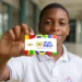 Adolescente segurando cartão Pé de Meia com cores vibrantes e logo do programa de poupança para ensino médio