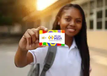 Jovem estudante segurando cartão colorido Pé de Meia com logo e chip em fundo desfocado