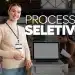 Mulher sorridente com crachá apresentando processo seletivo em escritório moderno e equipe ao fundo
