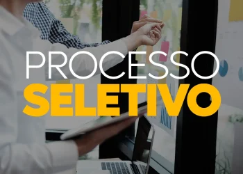 Pessoas planejando processo seletivo com post-its em parede de vidro e laptop aberto