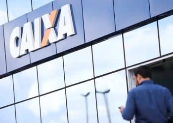 Fachada moderna da Caixa Econômica Federal com um funcionário entrando, simbolizando a oportunidade do concurso Caixa 2025 para carreira pública.