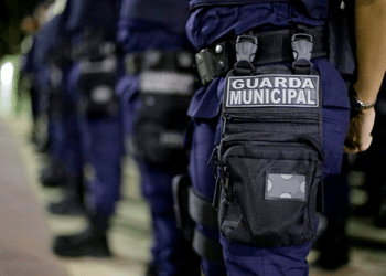 Guarda Municipal usando uniforme azul e pochete preta, formando fila.