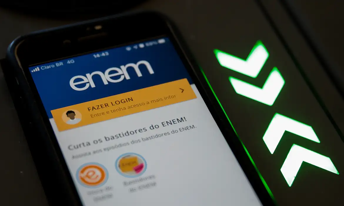 Aplicativo ENEM na tela do celular com login Celular mostrando tela do aplicativo ENEM com opção de login destacado