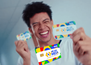 Jovem sorrindo enquanto segura dois cartões do programa Pé-de-Meia.