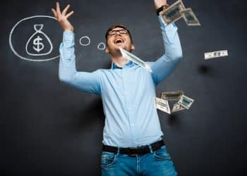 Homem de camisa azul joga notas de dinheiro ao ar com desenho de saco de dinheiro ao fundo Legenda: Homem alegre gesticula enquanto dinheiro voa no ar, simbolizando sucesso financeiro e realização de sonho.