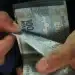 Mãos contando cédulas de cem reais representando o pagamento de mil reais do incentivo Pé-de-Meia.