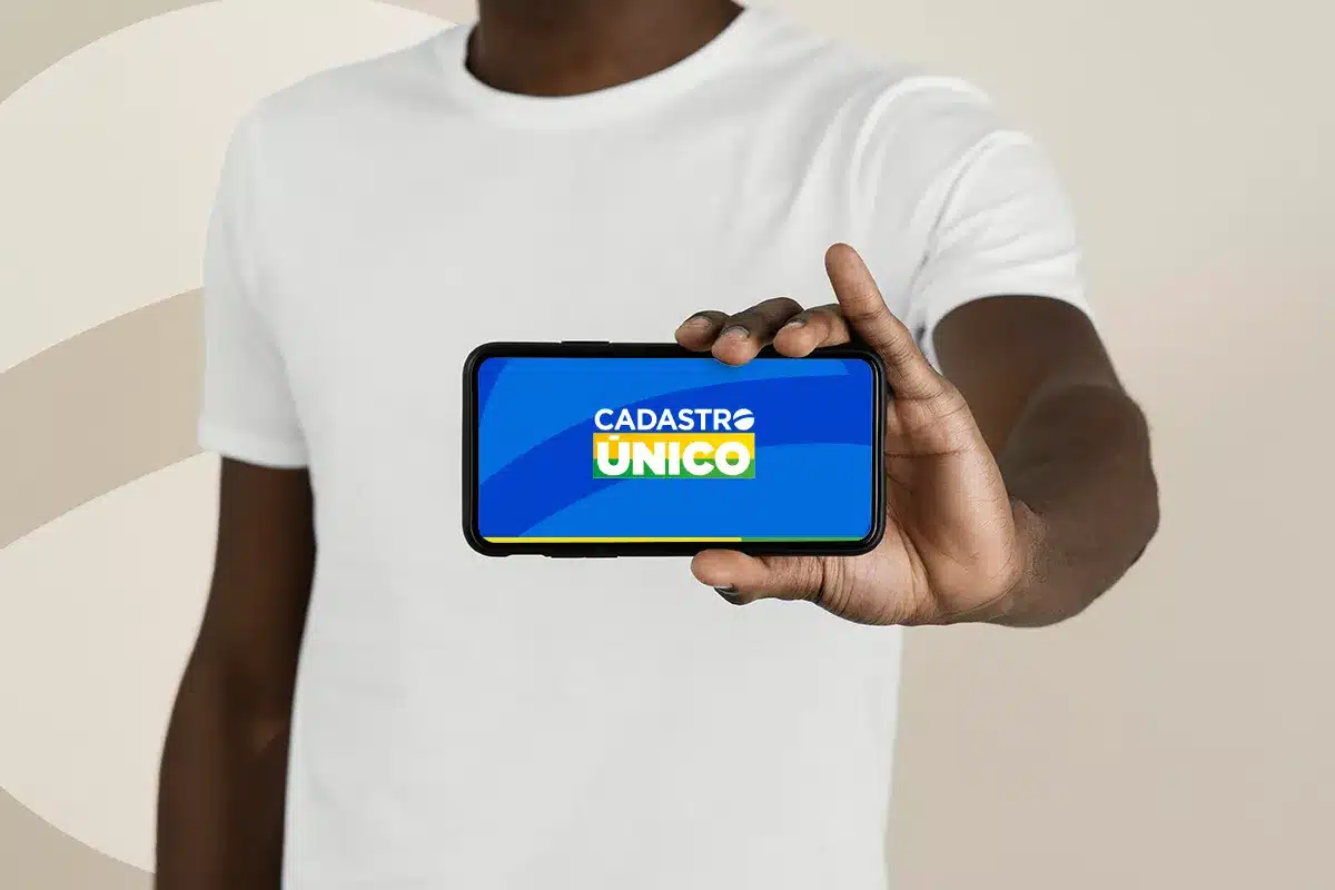 Cadastro Único mostrado em smartphone na mão Pessoa segurando celular com a tela exibindo o logo do Cadastro Único em azul, branco, amarelo e verde