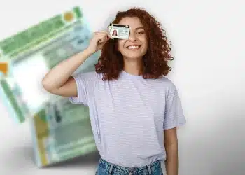 Jovem mulher sorrindo e segurando carteira de motorista perto do rosto com fundo desfocado.